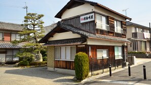 Una casa tradicional japonesa con fachada de madera, un balcón y un cartel.