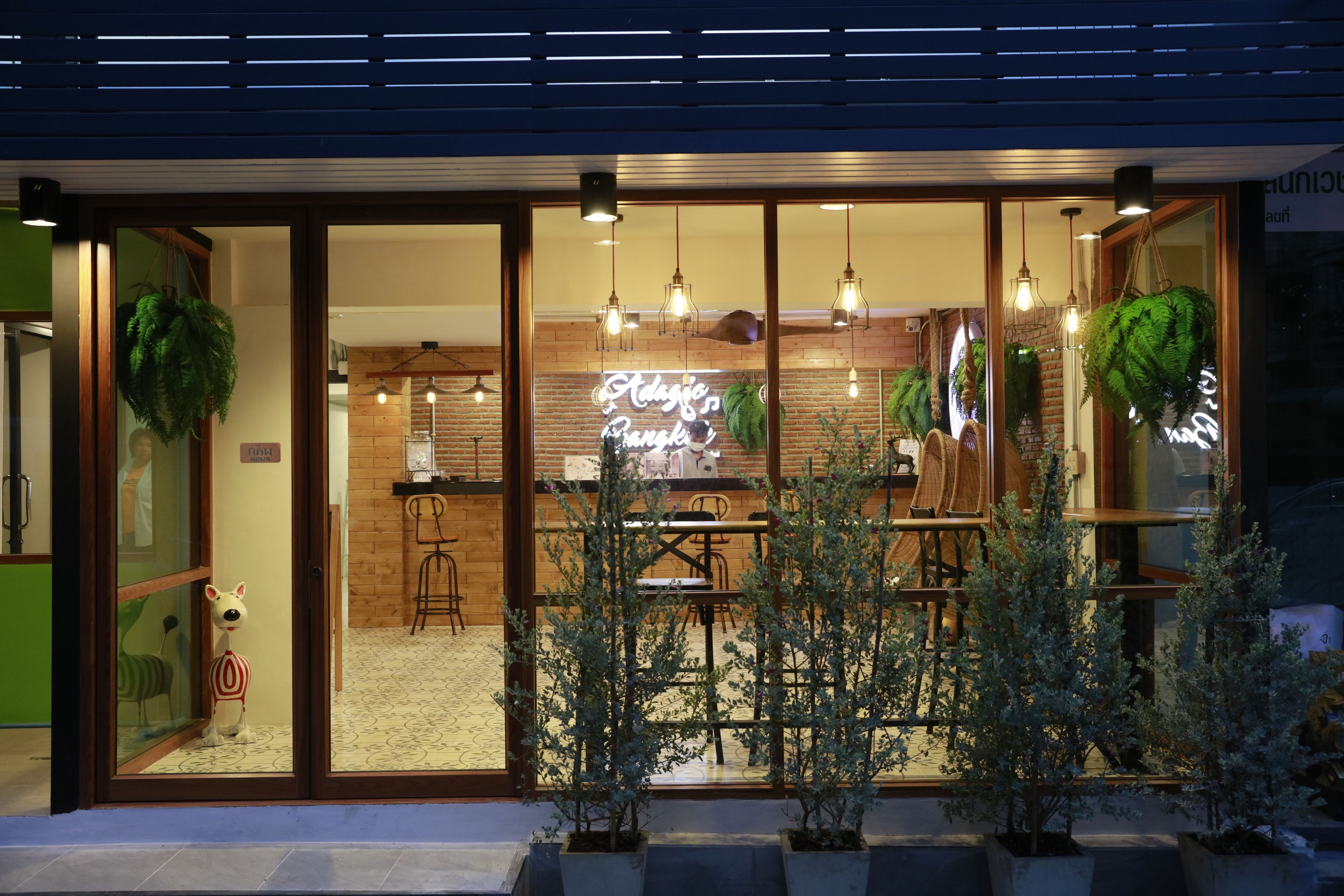 A restaurant with a brick wall, hanging plants, and a neon sign. - Adagio Bangkok (Bangkok)