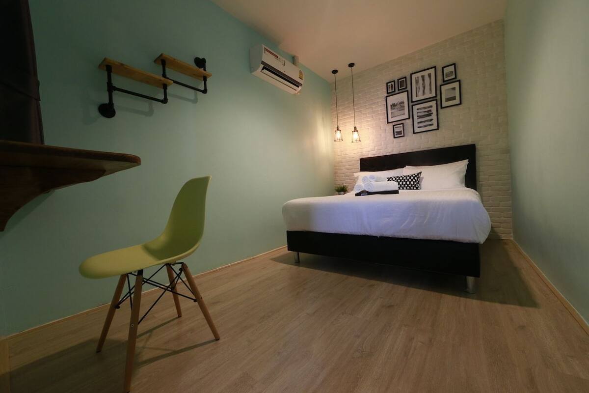 Une chambre comprenant un lit, une chaise, une étagère fixée au mur et un appareil de climatisation.