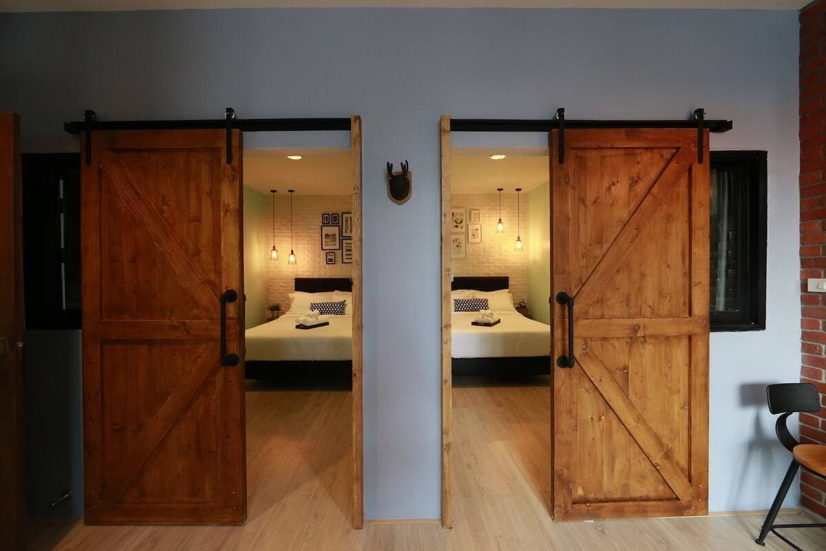 Une chambre avec deux lits, des portes coulissantes en bois, un mur en briques et une petite table.