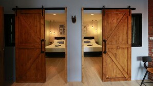 A room with two beds, wooden sliding doors, a brick wall, and a small table with a chair. - Adagio Bangkok (Bangkok)