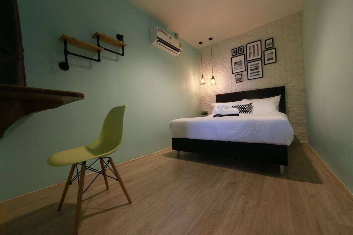 Une chambre comprenant un lit, une chaise, une étagère fixée au mur et un appareil de climatisation.