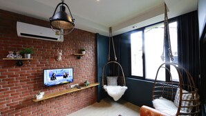 A living room with a brick wall, a TV, a hanging chair, and a sofa. - Adagio Bangkok (Bangkok)