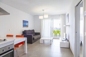 Una sala de estar moderna con comedor, un sofá, una mesa de centro y vistas al exterior.