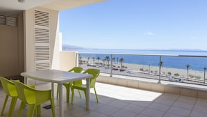 A balcony with a table and chairs, overlooking a beach and the sea. - Apartamentos Mar y Sal (Roquetas de Mar)