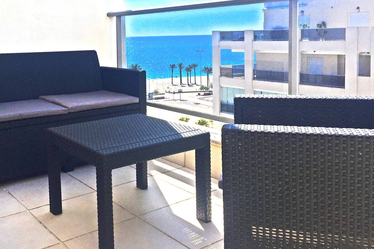 A balcony with a dark-colored sofa, a small table, and wicker chairs.
