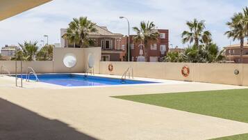 Una piscina con un flotador salvavidas, rodeada de palmeras y un edificio con tejado de baldosas.