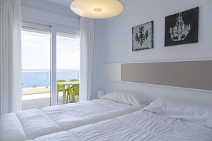 Habitación de hotel con cama, vistas al mar y dos obras de arte en la pared.