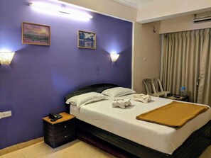 Habitació d'hotel amb llit, taules de nit, una làmpada i una finestra amb cortines.