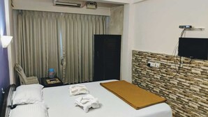 Habitación de hotel con cama, una silla, mesita de noche, televisor y pared con diseño de piedra.
