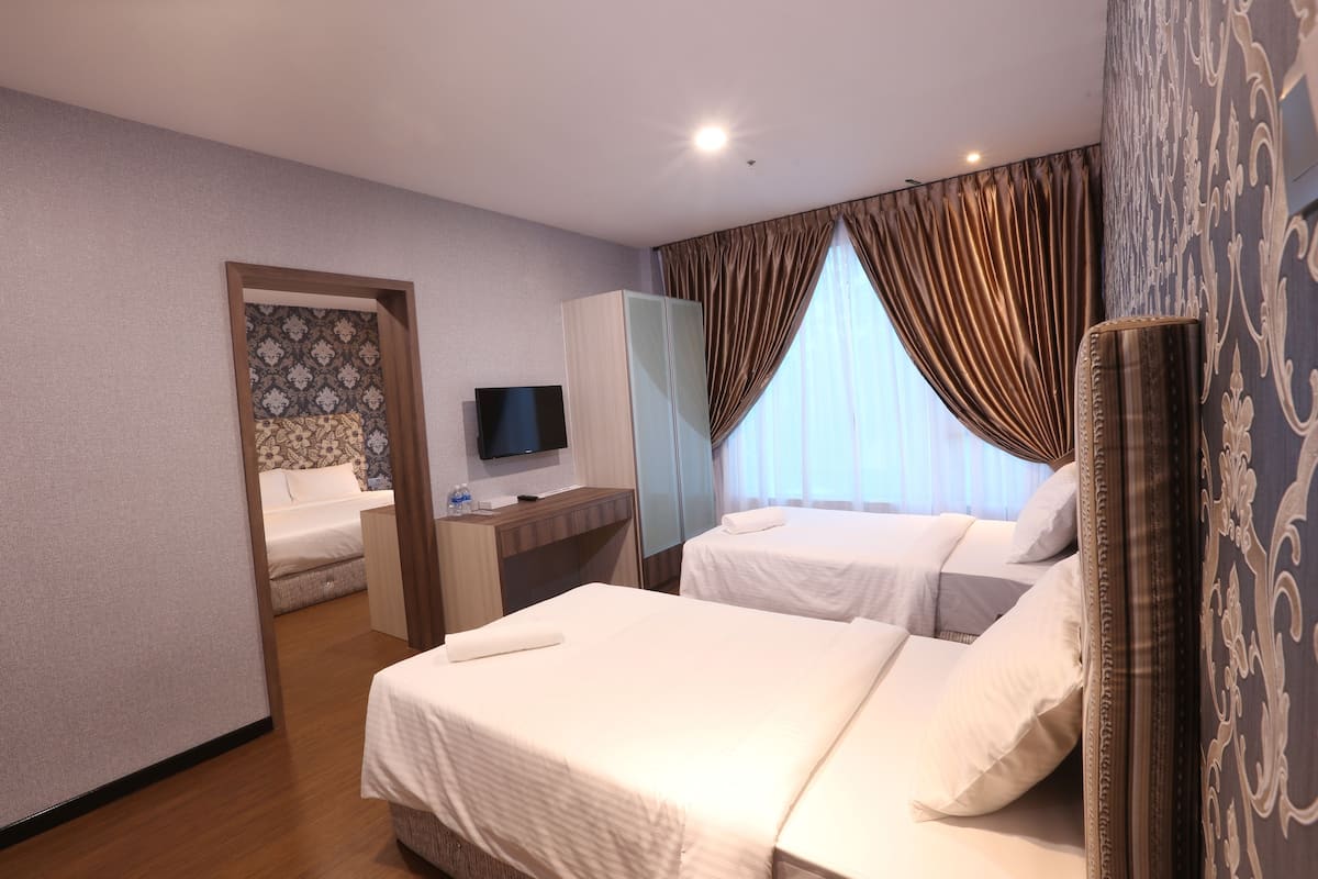 Une chambre d’hôtel avec deux lits, une télévision, un bureau et un miroir.