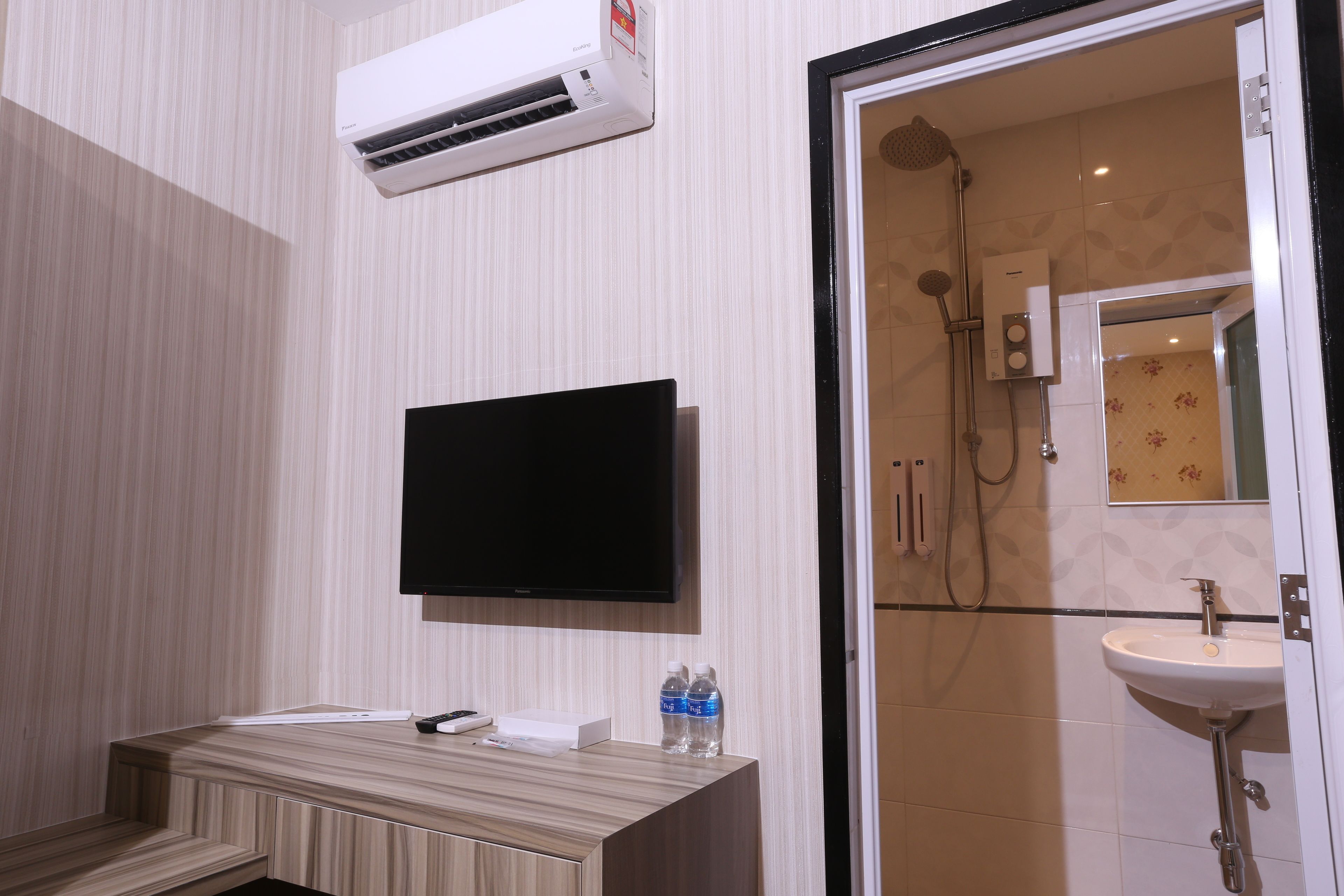 A modern bathroom with a wooden vanity, a mounted TV, and a glass shower enclosure.