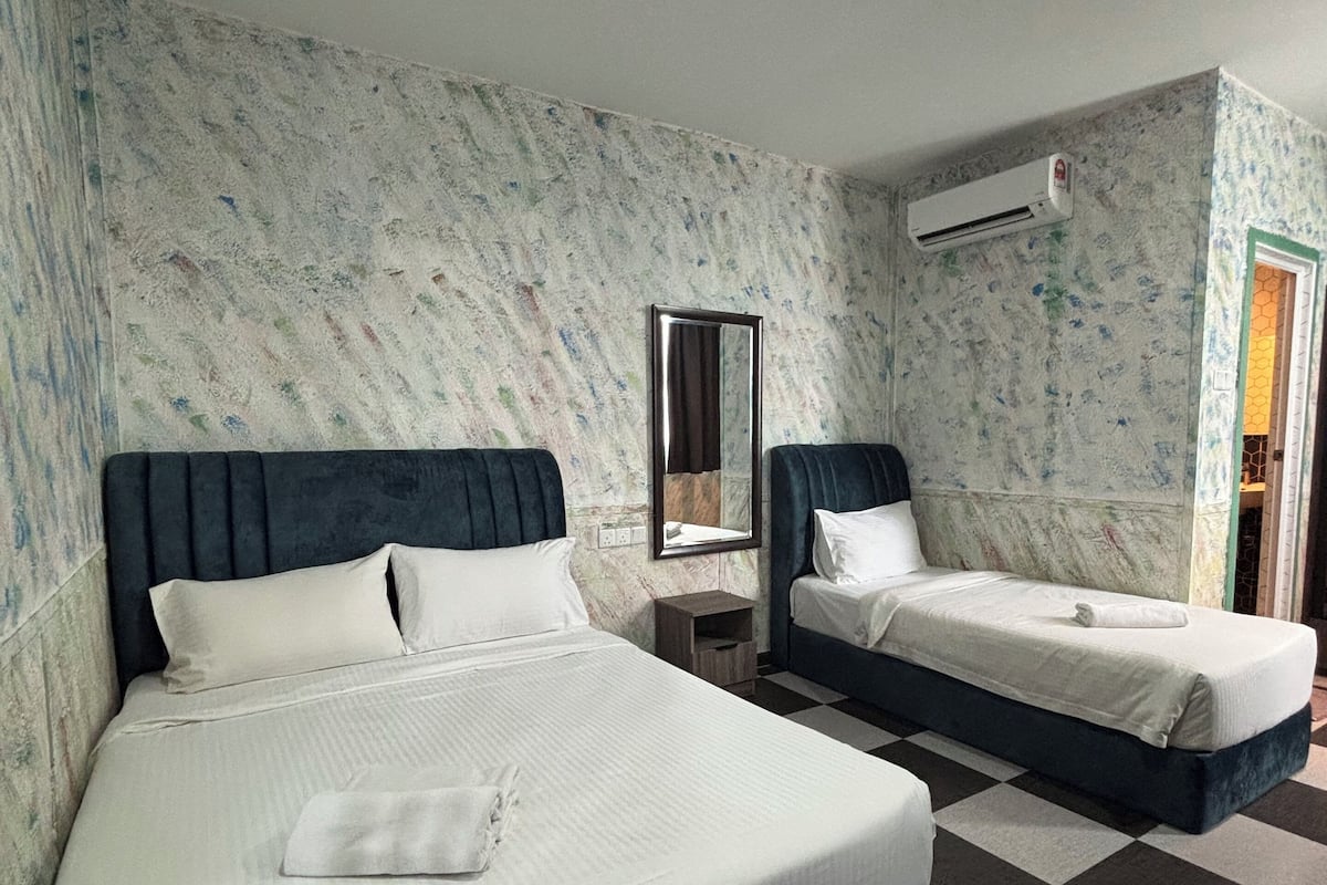Une chambre d’hôtel avec deux lits, un sol à carreaux, un miroir et un appareil de climatisation.