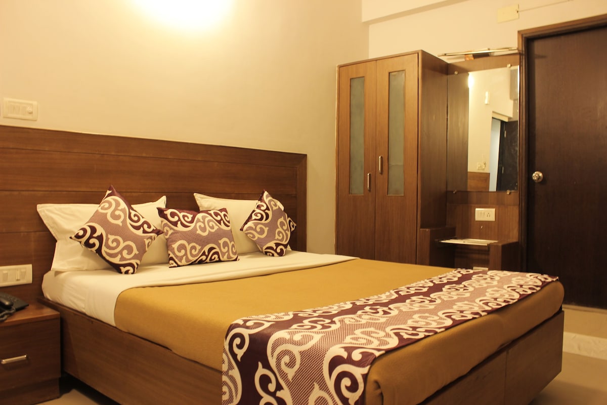 A neatly made bed with patterned pillows, a wooden headboard, and a bedside table with a phone.