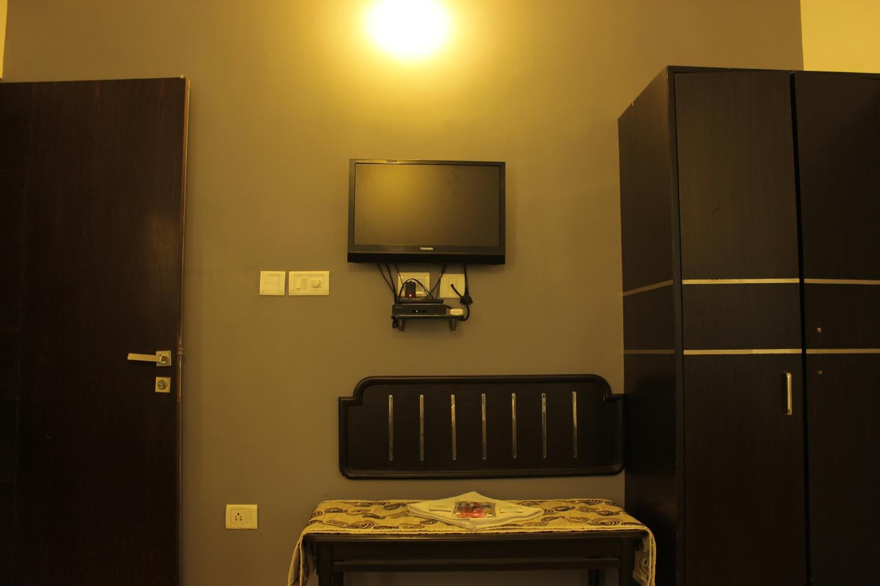 Una habitación con una cama, televisión montada en la pared y un armario.
