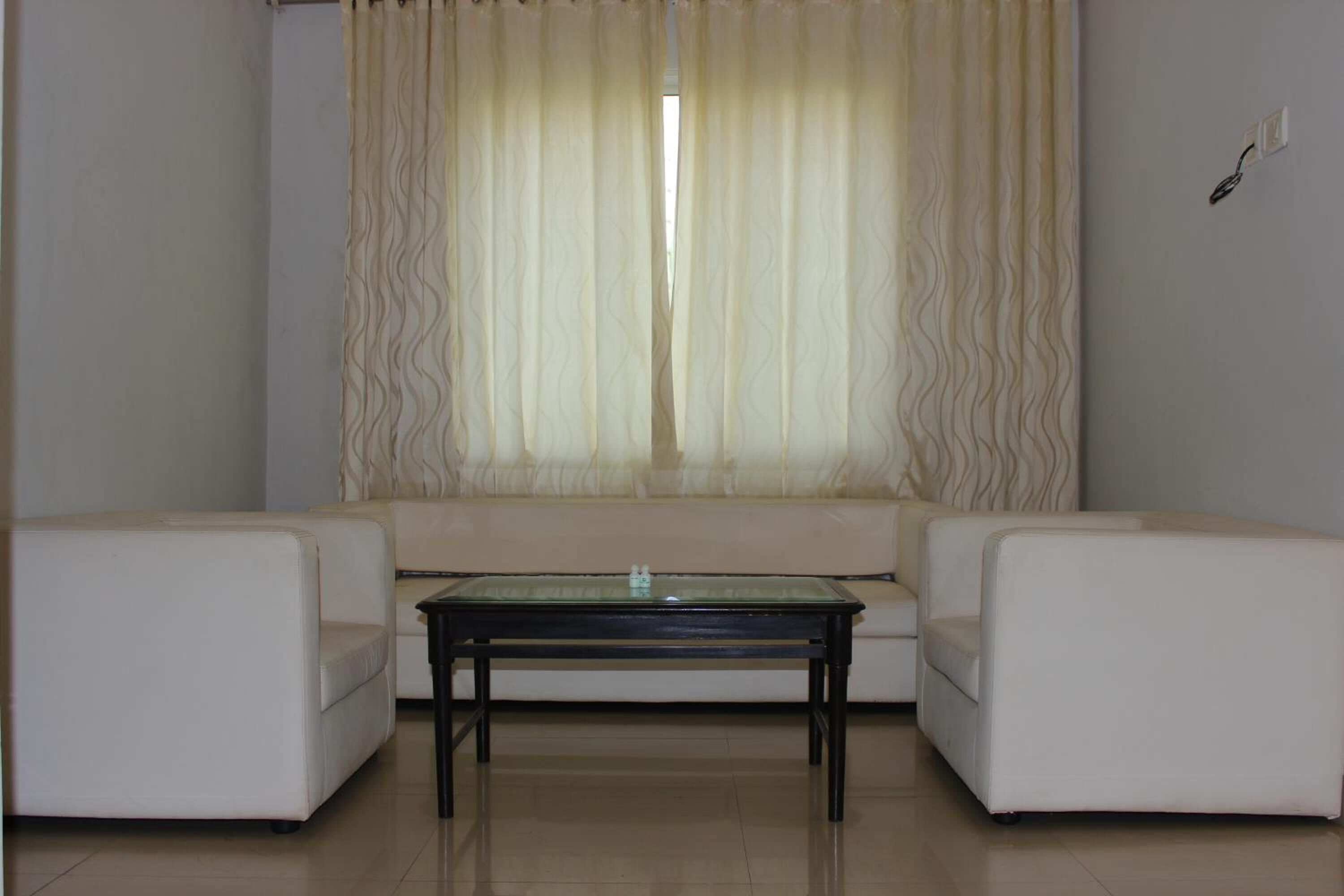 Una sala de estar con un conjunto de sofá, una mesa de centro y un ventanal con cortinas.