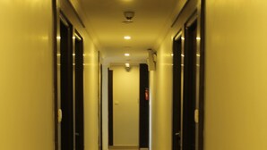 Un long couloir étroit, avec des portes de chaque côté, qui mène à une pièce au bout.