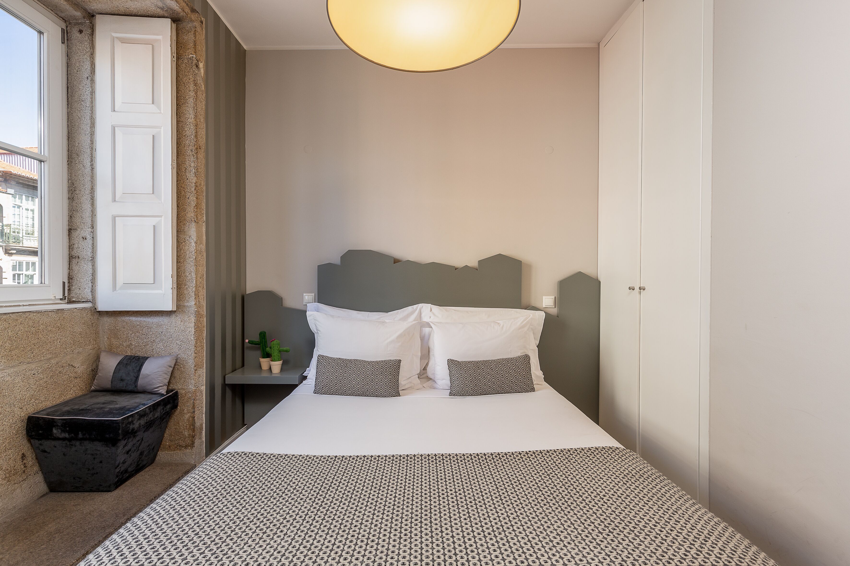 A neatly arranged bedroom with a bed, bedside tables, and a small seating area.