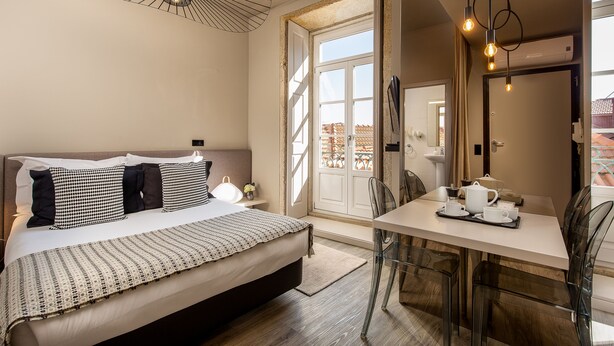 A bedroom with a bed, bedside table, and a dining area with a table and chairs. - YOUROPO - Clérigos (Porto)
