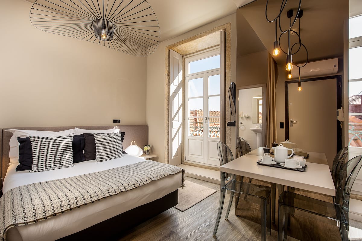 A bedroom with a bed, bedside table, and a dining area with a table and chairs.
