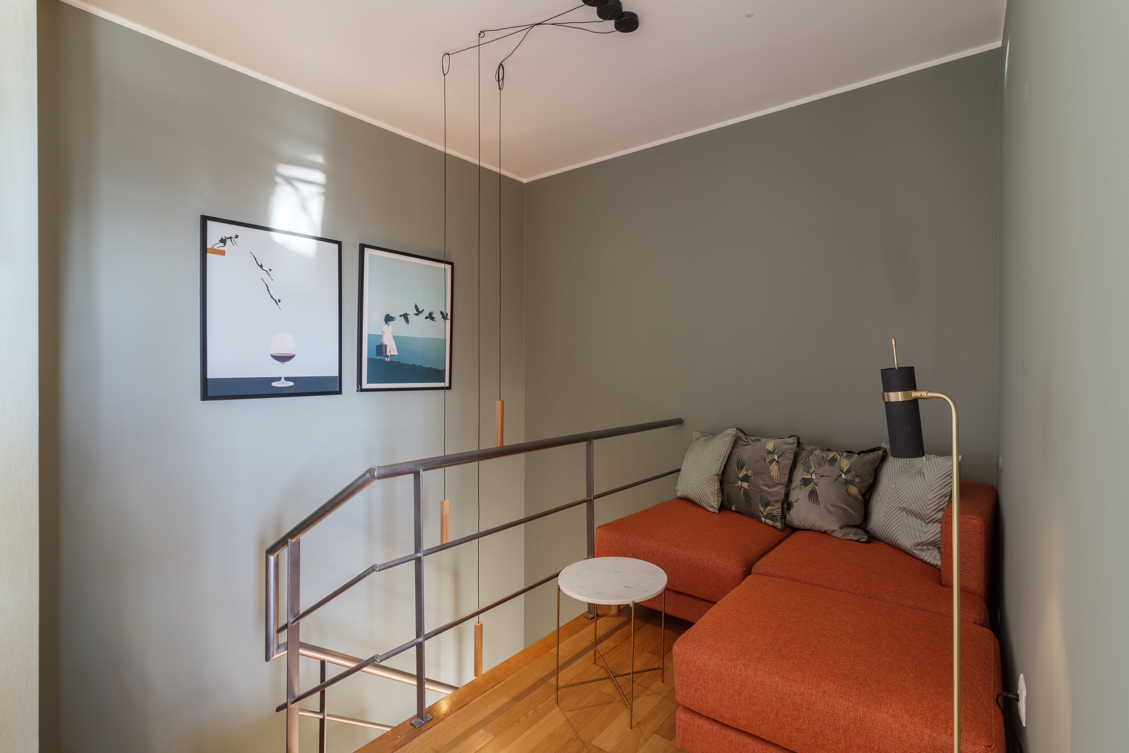 Ein modernes Interieur mit einer Treppe, einer Couch und zwei gerahmten Kunstwerken an der Wand.