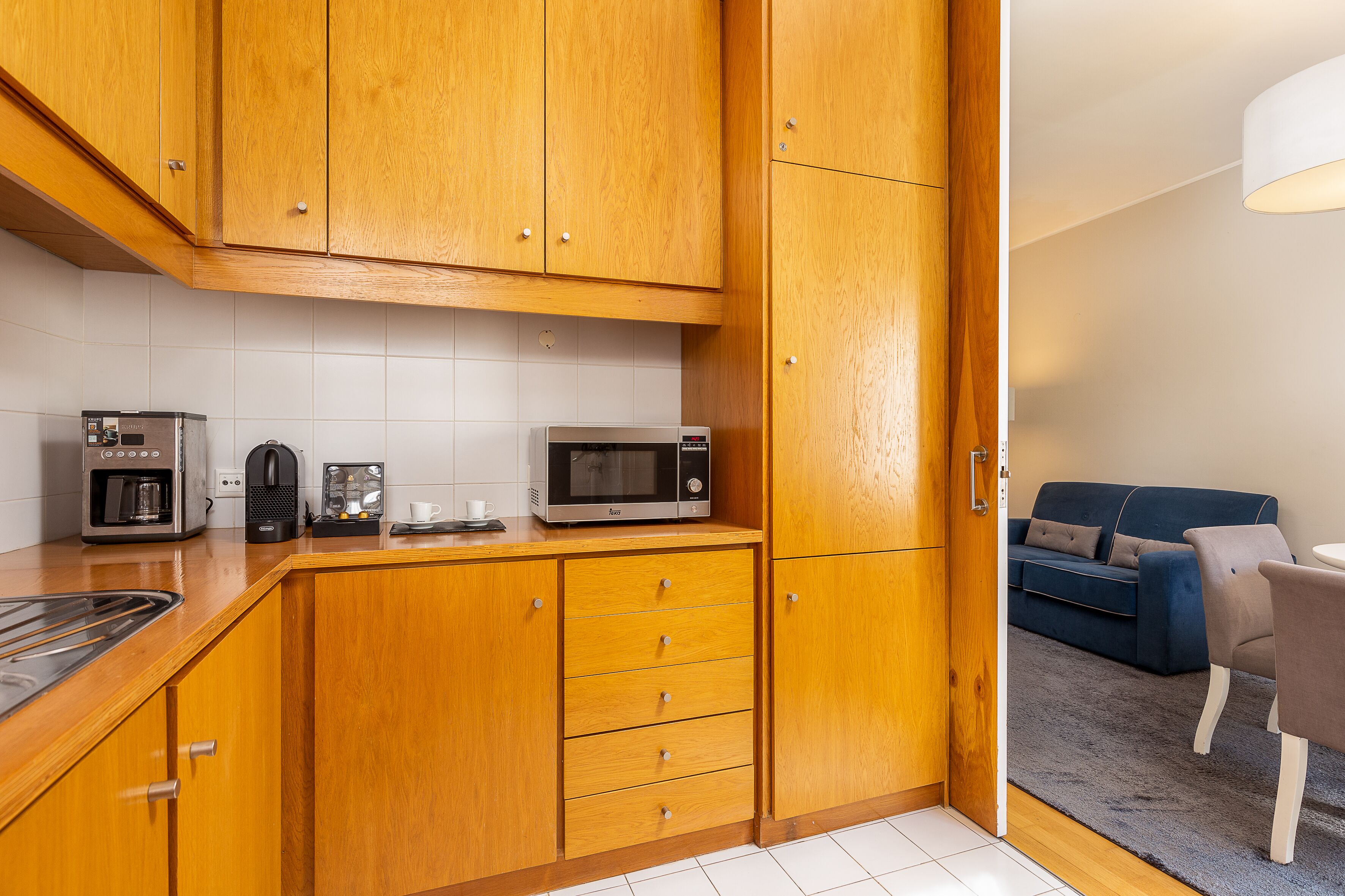 A compact kitchen with wooden cabinets, a microwave, a coffee maker, and a toaster.