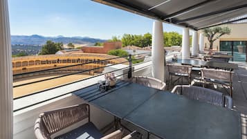 Terraza al aire libre con vistas a montañas, que cuenta con mobiliario de mimbre y una mesa grande.