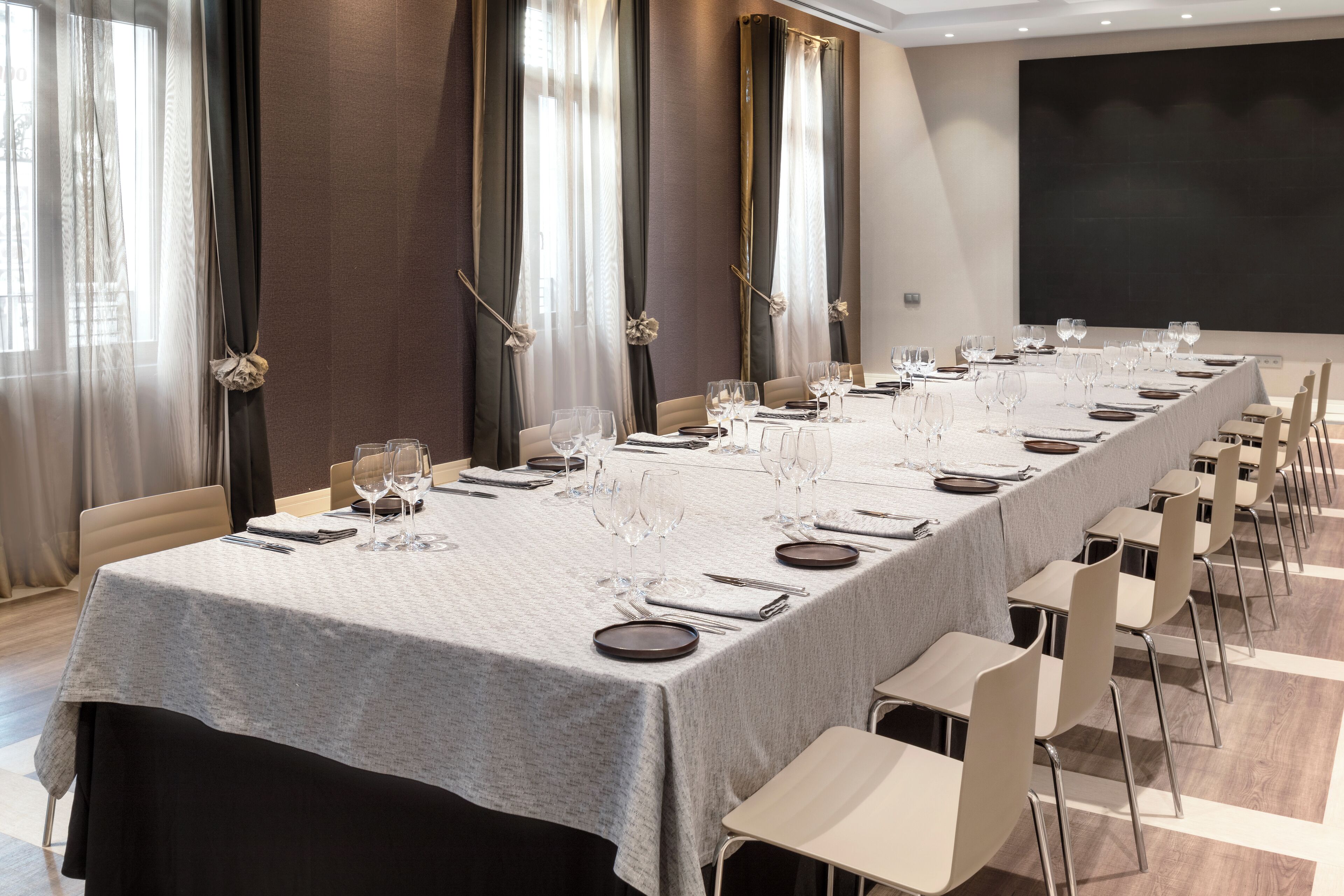 A conference room with a long table set for a meeting, equipped with chairs and a projector screen.
