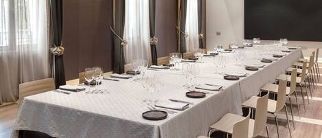 A conference room with a long table set for a meeting, equipped with chairs and a projector screen.