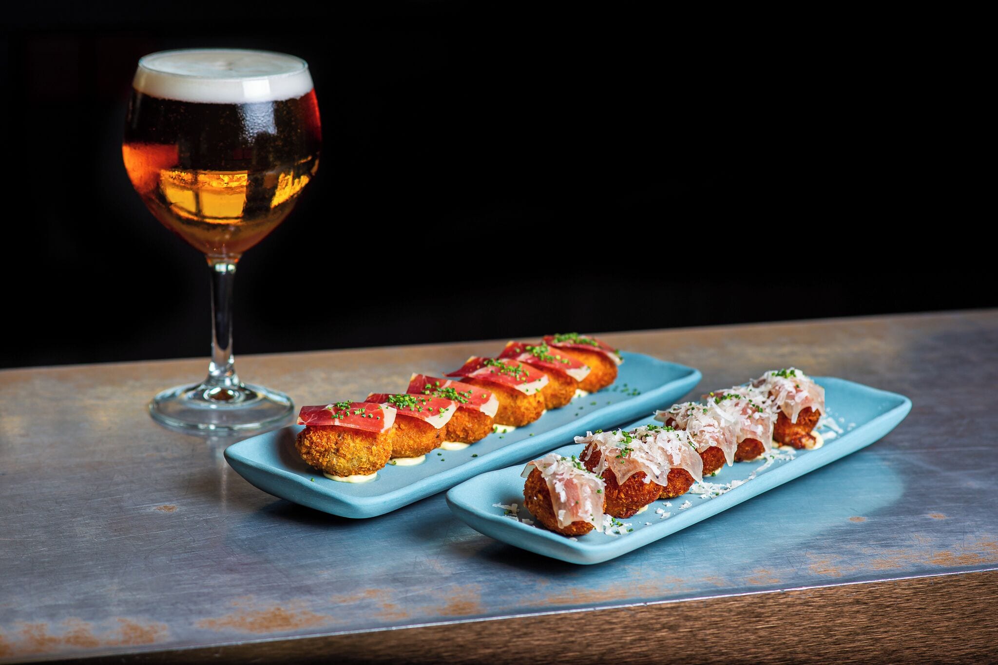 Una mesa con dos platos rectangulares azules llenos de comida y un vaso de cerveza.