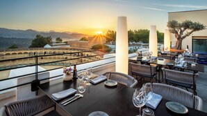 A restaurant with tables set for dining, overlooking a scenic view of mountains and a sunset. - Catalonia Ronda (Ronda)