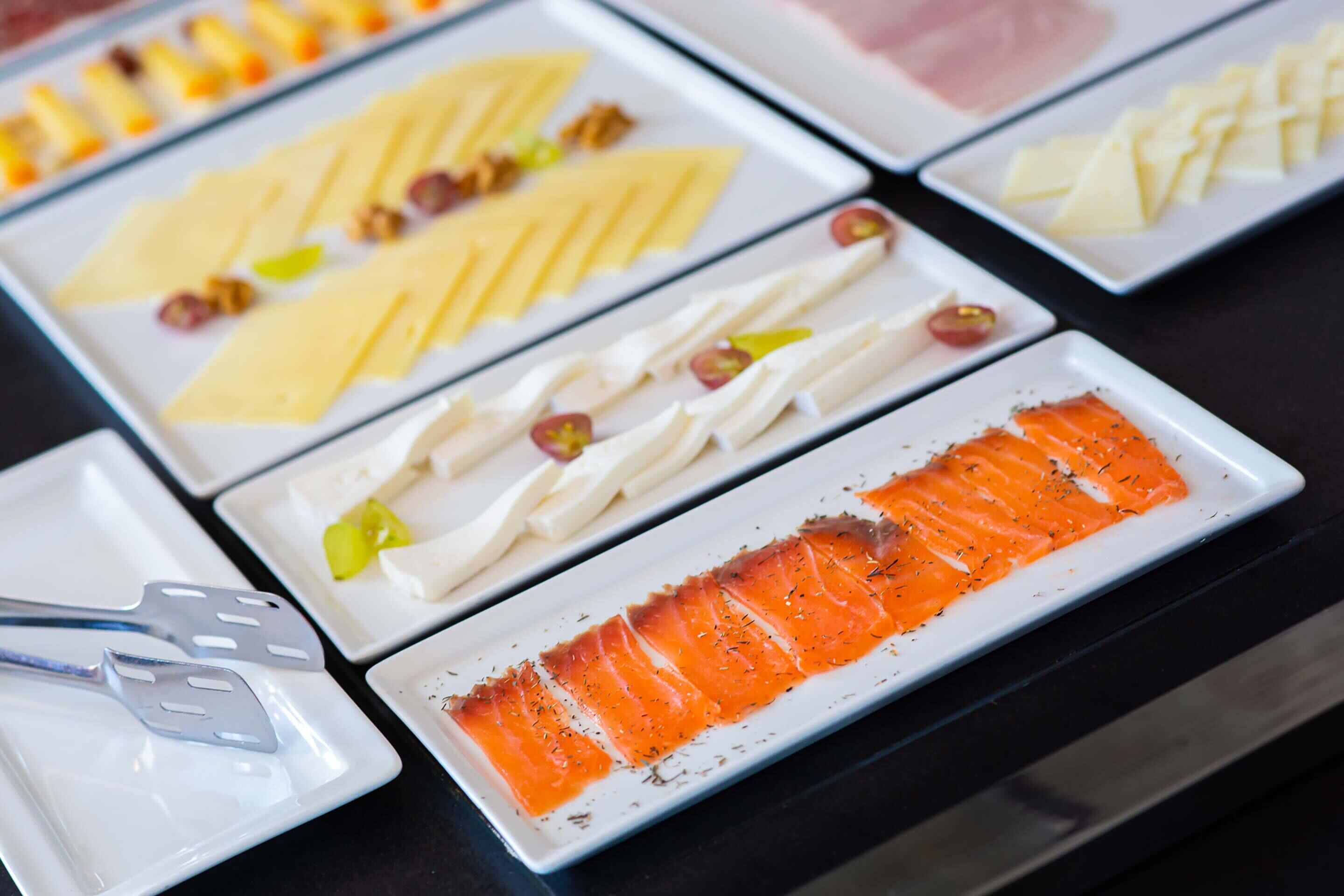 A buffet with various food items including salmon, cheese, and other dishes.