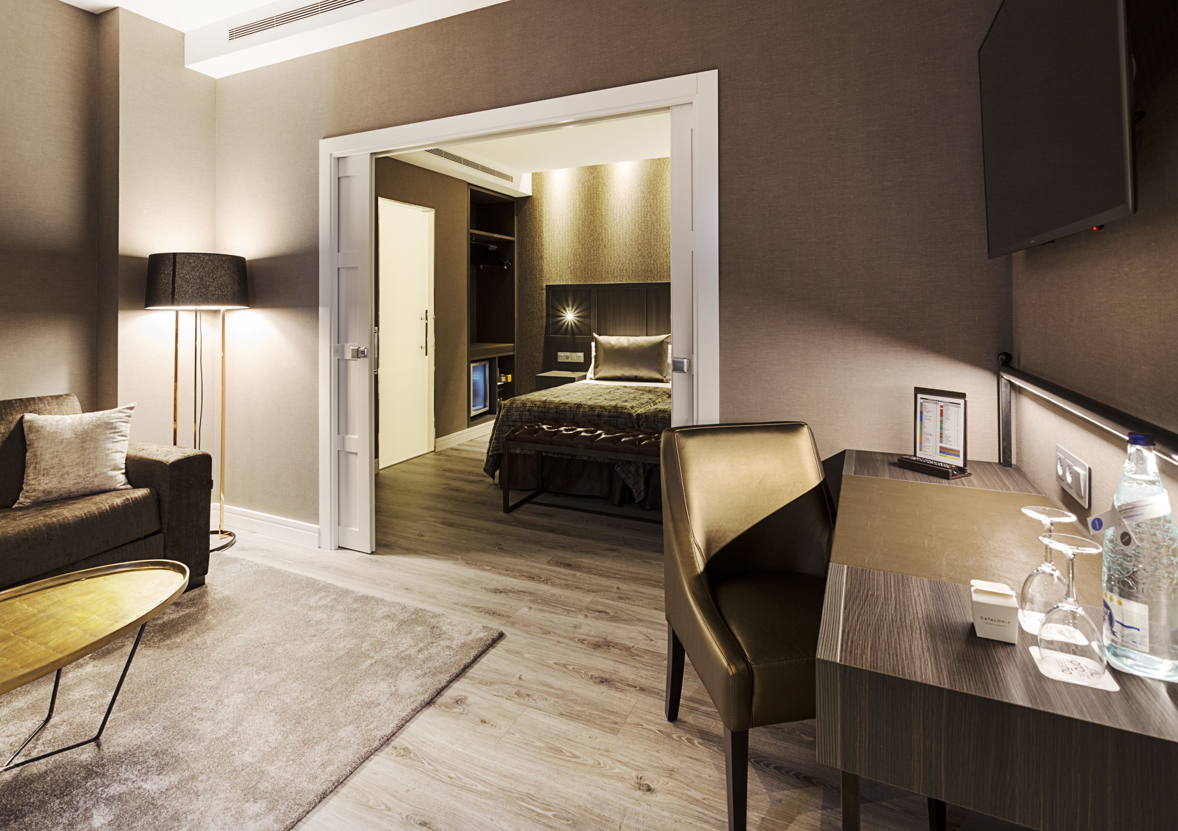 Une chambre d’hôtel moderne équipée d’un lit, d’un bureau, d’une chaise, d’un canapé, d’une lampe et d’un téléviseur.