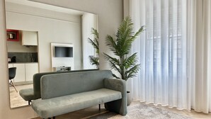 A living room with a grey sofa, a large mirror, a TV, and a potted plant. - YOUROPO - Capela (Porto)