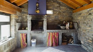 A stone fireplace with a wooden ceiling and a rustic interior. - Leyendas del Pirineo (Fiscal)