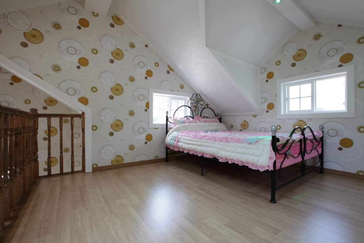A bedroom with a bed, a window, and a patterned wall.