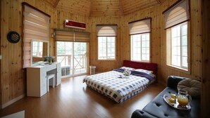 A wooden cabin bedroom with a bed, a desk, and a seating area. - Ecopia Pension (Pyeongchang)