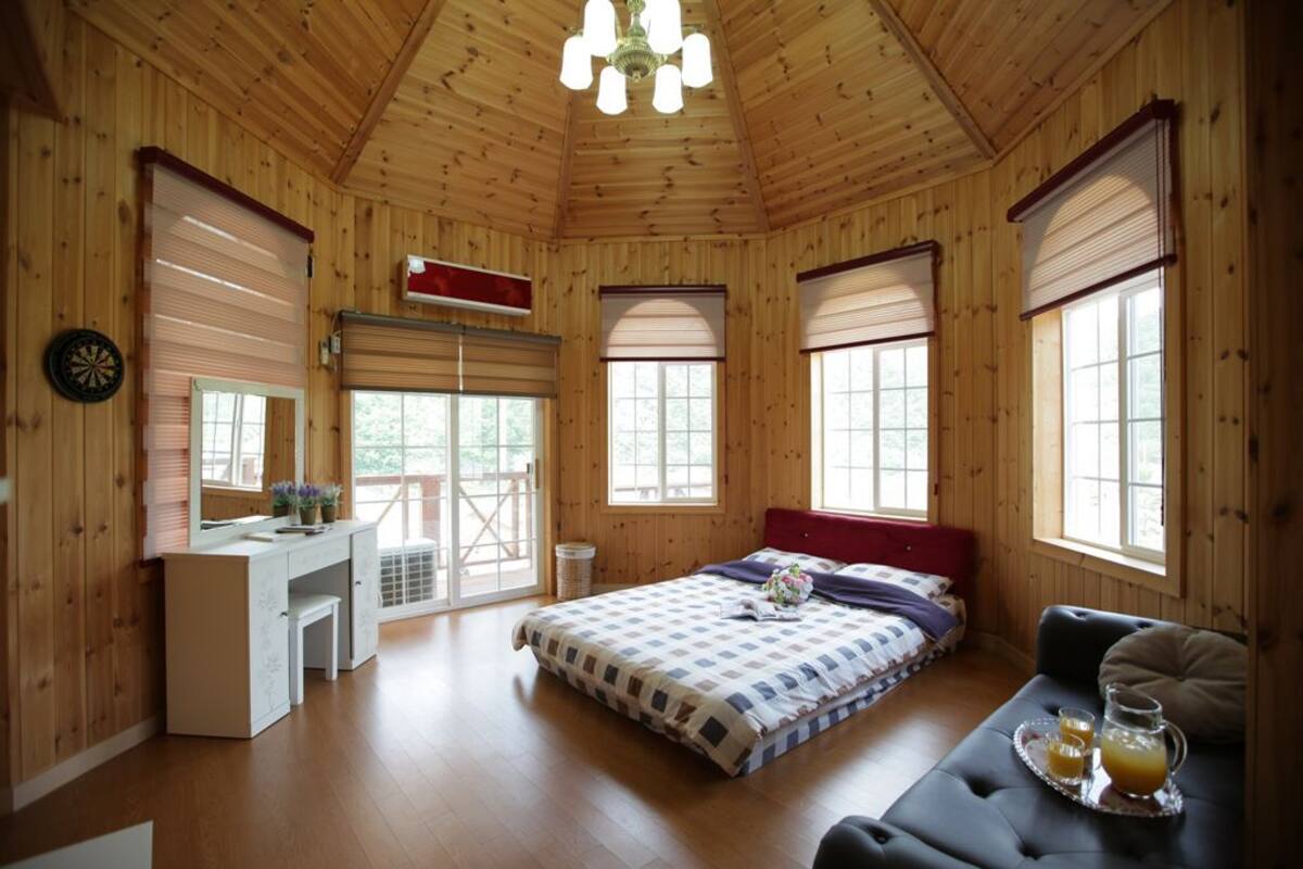 A wooden cabin bedroom with a bed, a desk, and a seating area.