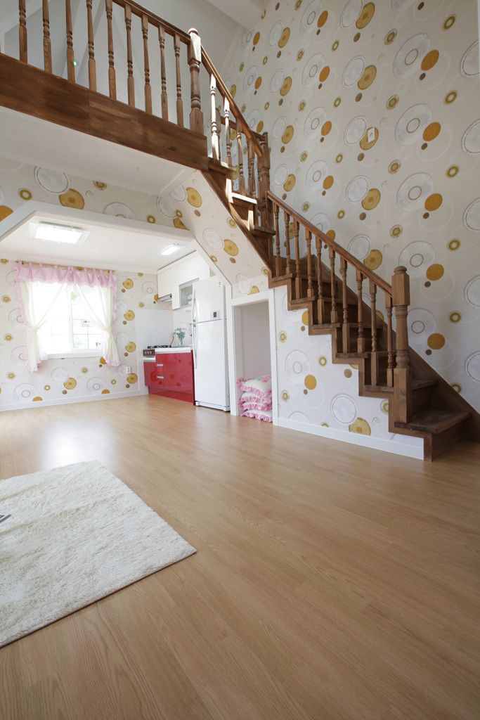 A spacious living area with a wooden staircase, a kitchen area, and a patterned wall.