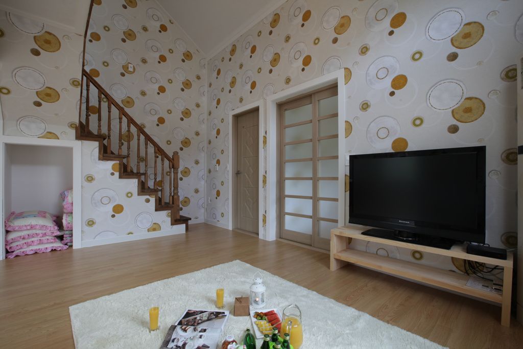 A living room with a wooden staircase, a flat-screen TV on a wooden stand, and a white rug with a breakfast setup.