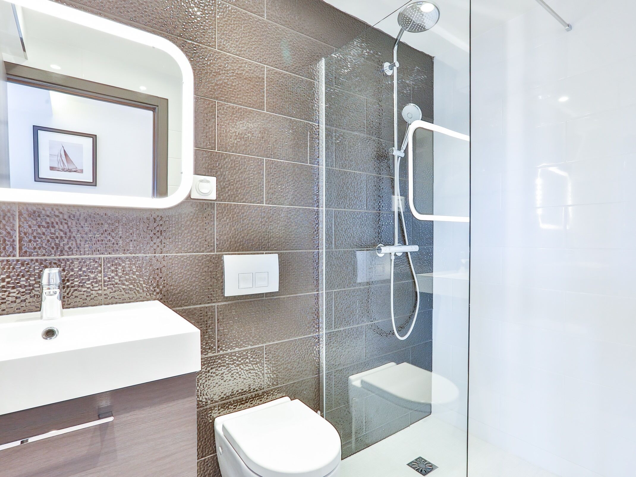A modern bathroom with a glass-enclosed shower, a white sink, and a toilet.