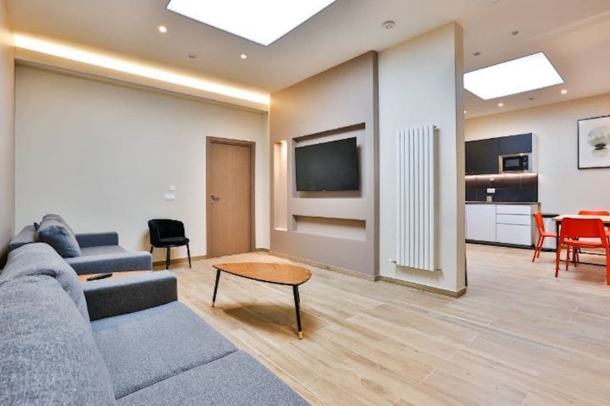 A modern living room with a sofa, a coffee table, and a TV mounted on the wall.