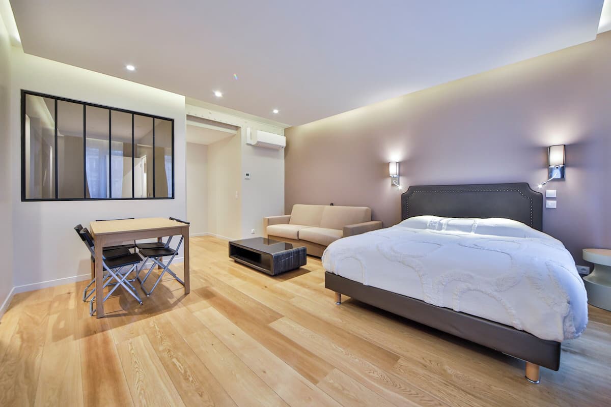 A modern bedroom with a bed, a sofa, a desk, and a mirror.