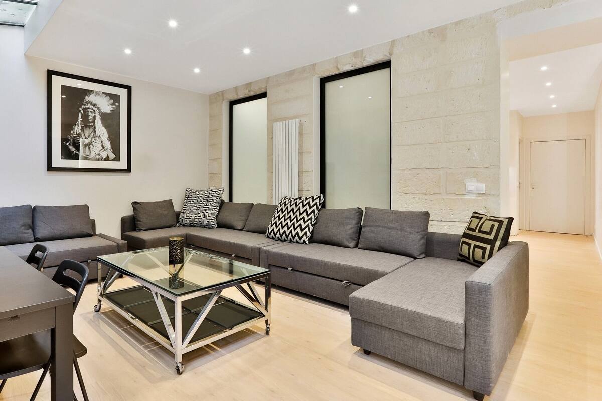 A modern living room with a sectional sofa, a glass coffee table, and a framed picture on the wall.