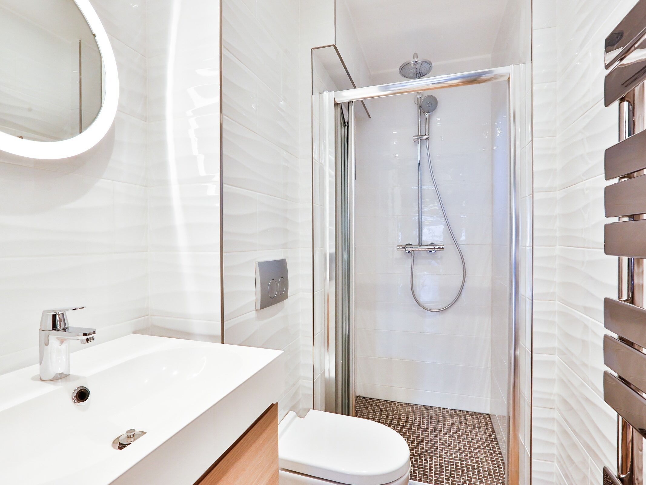 Une salle de bain moderne avec une douche à parois de verre, un lavabo blanc et des toilettes.