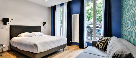 Une chambre à coucher moderne avec un lit, un canapé et une fenêtre avec des rideaux.