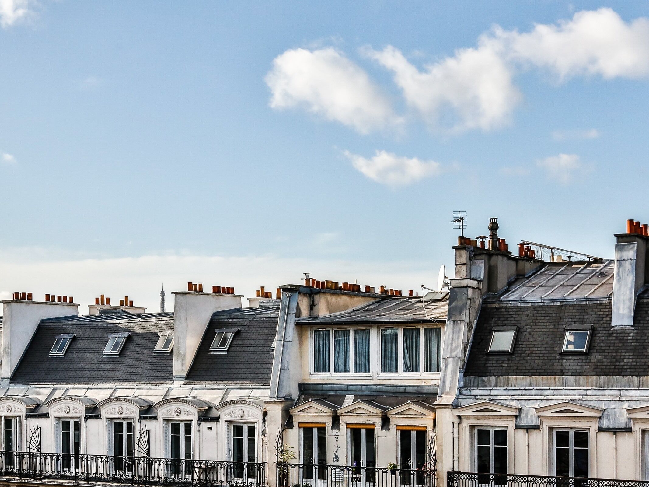 Una hilera de edificios históricos de estilo europeo, con varios pisos y detalles arquitectónicos clásicos como molduras ornamentales y barandillas decorativas.