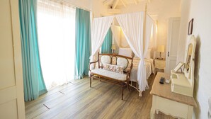 A bedroom with a four-poster bed, a bedside table with a lamp, and a mirror. - Kupina Otel (Cesme)