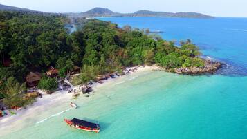 Escape to a secluded beachside haven surrounded by lush greenery and a tranquil turquoise sea.