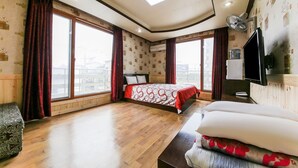 A hotel room with a large bed, a TV mounted on the wall, and a view of the city through large windows. - Venus Motel&Pension (Boryeong)